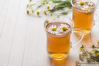 Ahşap arka plan üzerinde çay ve papatya çiçek fincan.