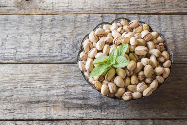 Lezzetli tuzlu fıstık ve ahşap zemin üzerine taze nane yaprakları