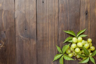 Ahşap bir masa arka plan boşluk bir kopyasıyla üzerinde beyaz üzüm demet.