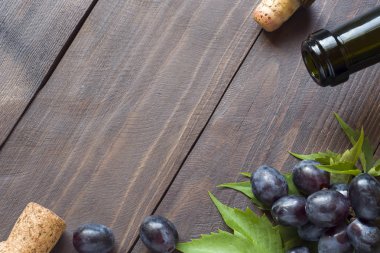 Avuç üzüm, kırmızı ve beyaz şişe şarap ve ahşap masa arka plan kopya alanı ile üzerinde mantar.