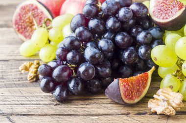 Taze sonbahar meyve natürmort. Üzüm siyah ve yeşil, incir ve kopya alanı ile ahşap bir masa yapraklarda