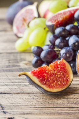 Taze sonbahar meyve natürmort. Üzüm siyah ve yeşil, incir ve kopya alanı ile ahşap bir masa yapraklarda