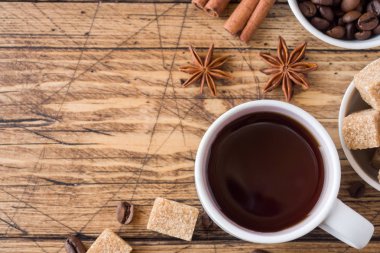 Bir fincan kahve, kahverengi şeker ve tarçın ile Anason ahşap arka plan üzerinde. Kopya alanı.