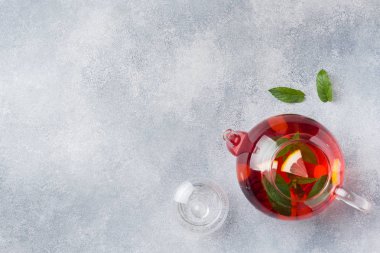 Cam demlik çay, nane ve limon ile kopya alanı gri tabloda.