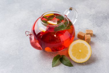 Cam demlik çay, nane ve limon ile kopya alanı gri tabloda.