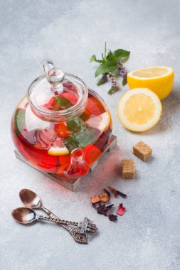 Cam demlik çay, nane ve limon ile kopya alanı gri tabloda.