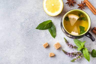 Fincan çay, nane ve limon, kahverengi şeker tarçın ve anason kopya alanı gri bir tablo.