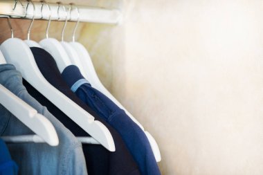 Mavi ve gri t-shirt askıları dolabın üzerinde. Görüntü. Seçici odak