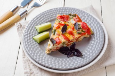 Beyaz ahşap bir masa üzerinde bir tabakta sebze ile hizmet veren omlet.