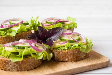 Peynir, salatalık ve soğan kepekli ekmek üzerinde açık sandviçler. Seçici odak