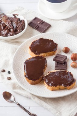 Çikolatalı fındık sandviçle plaka üzerinde yayılmış. Kahve tablo