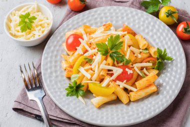 Makarna, domates soslu makarna ve peynir ahşap bir masa üzerinde bir tabak içinde.