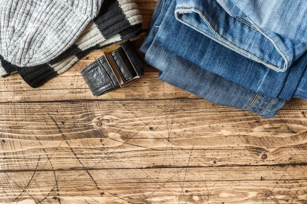 Jeans clothes and accessories on brown wood background.