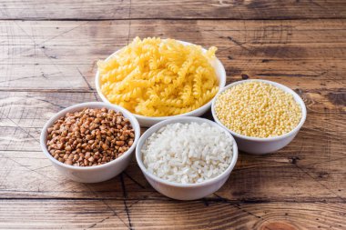 Kabuğu çıkarılmış tane bakkal kuru. Pirinç Makarna buğday ve darı ahşap arka plan üzerinde