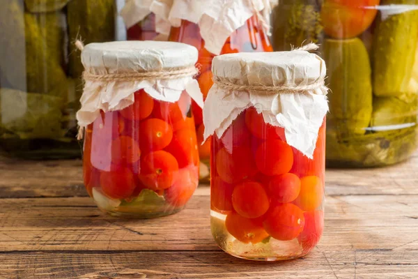 Homemade canned vegetables in cans. Pickled tomatoes and cucumbers in a rural style