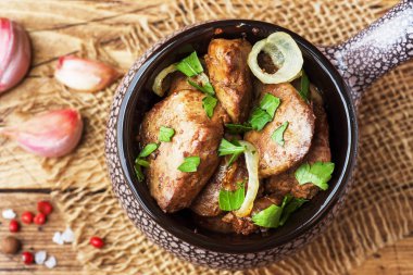 Pişmiş tavuk karaciğer ahşap rustik masa üzerinde seramik cocotte soğan ile