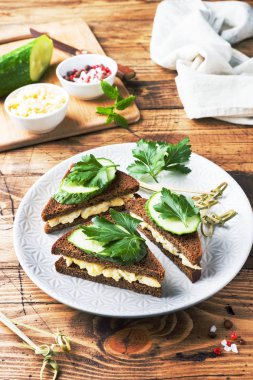 Sahanda yumurta, salatalık ve ahşap rustik zemin üzerine maydanoz ile sandviç