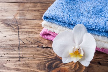 Spa ve sağlıklı yaşam konsepti üzerine ahşap arka plan. Renkli Terry havlu ve bir beyaz orkide çiçek