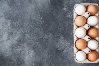 Karanlık bir acımasız tabloda bir karton kutu içinde tavuk yumurta