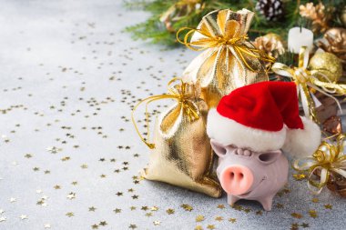 Domuz hediyeler Noel ağaçları arka plan üzerine torba ile Noel Baba şapkalı bir rakam. Noel süsleri. Yeni yıl kavramı
