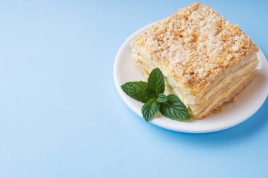 Mavi renkli bir arka plan üzerinde nane ile krem Napoleon yağlı vanilyalı dilim pastayla katmanı