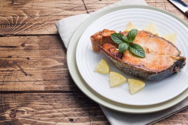 Limonlu bir tabakta Somon Balık pişmiş biftek. Ahşap masa