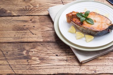 Limonlu bir tabakta Somon Balık pişmiş biftek. Ahşap masa