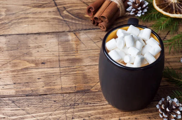 Hot chocolate with marshmallow cinnamon sticks, anise, nuts on wooden background, Christmas concept.