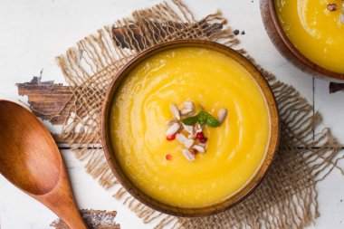 Işık kurullarında ahşap kase içinde baharatlar ile püre kabak çorbası