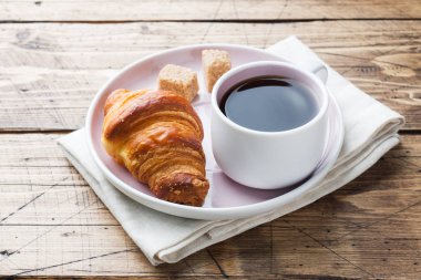 Bir tabak ve bir fincan kahve, ahşap arka plan, kahvaltı croissants alanı Kopyala