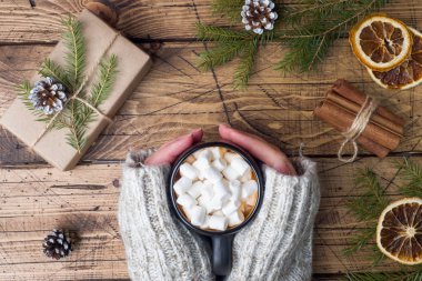 Sıcak çikolata hatmi ile el ele tutuşsun kadın tarçın, anason, fındık ile ahşap arka plan, Noel kavramı.