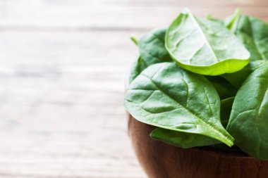 Taze ıspanak kapta rustik ahşap masa kopya alanı bırakır.