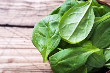 Taze ıspanak kapta rustik ahşap masa kopya alanı bırakır.