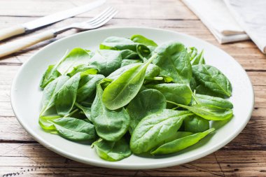 Taze ıspanak kapta rustik ahşap masanın üzerine bırakır.