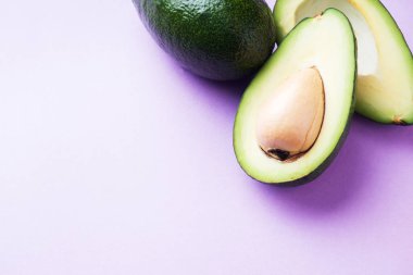 Avokado bütün ve kopya alanı ile pembe bir arka plan üzerinde kesme