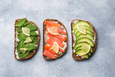 Ispanak ve avokado somon gri bir tablo ile açık sandviçler