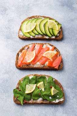 Ispanak ve avokado somon gri bir tablo ile açık sandviçler