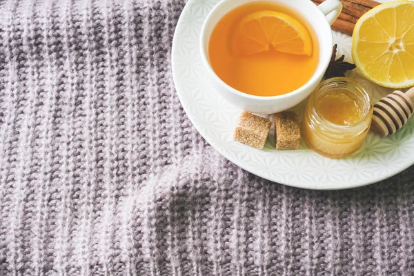 Cup of tea with lemon and cookies, honey and cinnamon sticks, star anise on the blanket.. Christmas, winter concept