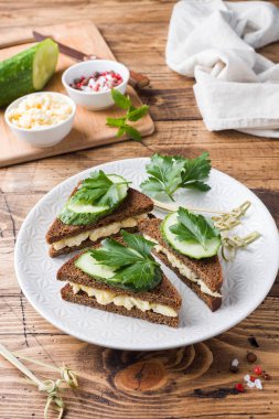 Sahanda yumurta, salatalık ve ahşap rustik zemin üzerine maydanoz ile sandviç