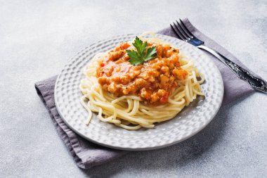 Spagetti makarna Bolognese masa beyaz plaka, gri üzerine.