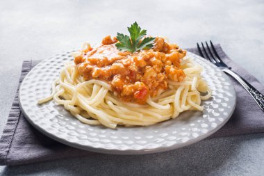 Spagetti makarna Bolognese masa beyaz plaka, gri üzerine.