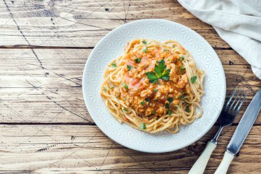 Spagetti makarna Bolognese beyaz tabakta, ahşap masa.