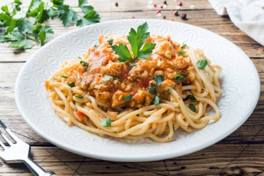 Spagetti makarna Bolognese beyaz tabakta, ahşap masa.