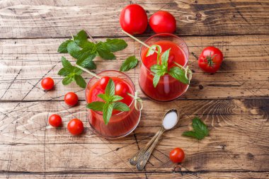 Domates suyu ile nane cam ve ahşap bir masa üzerinde taze domates. Sağlıklı organik gıda kavramı.