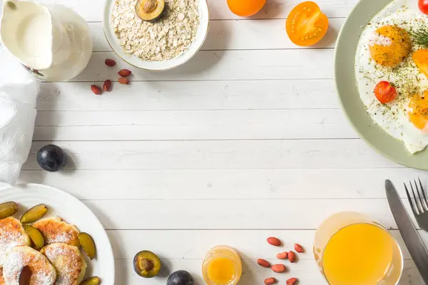 Концепция Завтрака Жареные Яйца Блинчики Сыром Сливы Овсянка Молоком Апельсиновый — стоковое фото