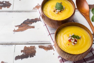 Işık kurullarında ahşap kase içinde baharatlar ile püre kabak çorbası