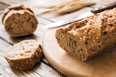 Ayçiçeği tohumu, susam ve keten ile taze ekmek kesme tahtası üzerinde parçalar halinde kesilmiş