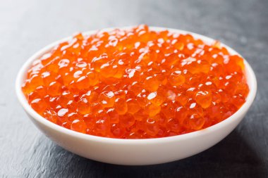 Kırmızı somon havyar karanlık bir masaya bir tabak içinde