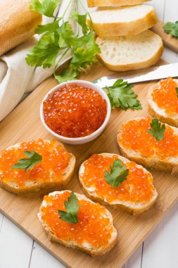Bir ahşap tahta üzerinde kırmızı somon havyar ile sandviçler. Beyaz masa üstü