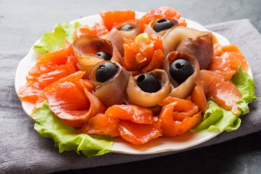 Bir tabak füme tuz, çiğ beyaz balık fileto ve somon sunan gurme restoranı. Yayın balığı, somon eti plaka yakın çekim üzerinde zeytinli ile incelik taze deniz ürünleri yemek.